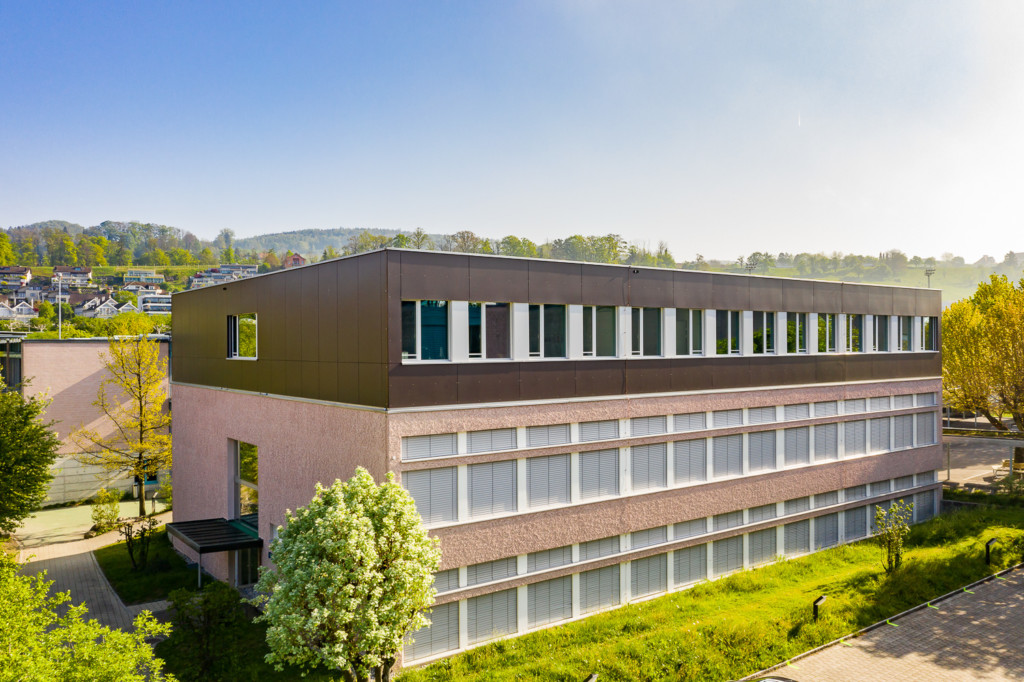Schulhausaufstockung in Meilen: Vollkern-Fassade aus grossformatigen Fassadenplatten – nach Wunsch lackiert l Krattiger Holzbau AG Amriswil