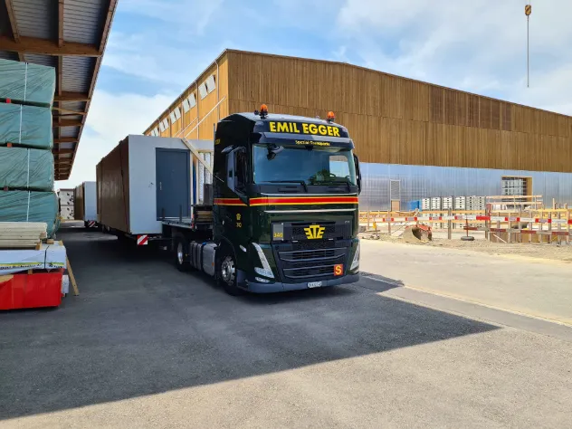 Tieflader mit UNUS-Modulen aus Holz bereits zur Abfahrt vor der Produktionshalle in Amriswil